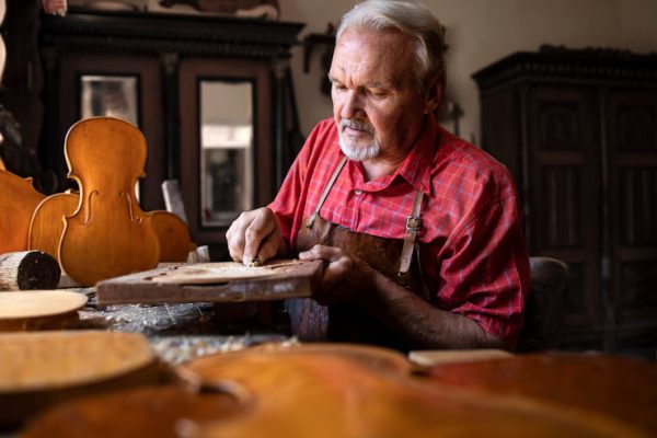 senior-carpenter-craftsman-carefully-carving-shaping-wood-his-woodworking-workshop_308072-332